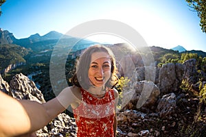 A woman takes a selfie on top of a mountain