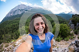 A woman takes a selfie on top of a mountain