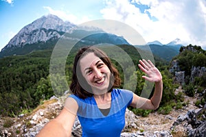 A woman takes a selfie on top of a mountain