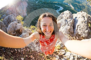 A woman takes a selfie on top of a mountain