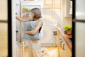 Woman takes some food from a fridge at night