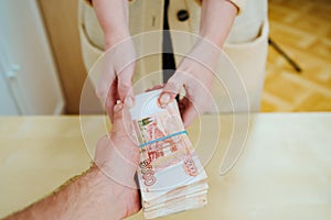 woman takes a stack of rubles tied with a rubber band.