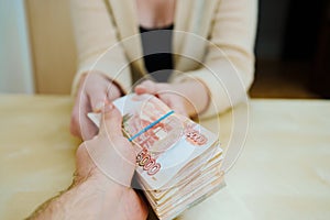 woman takes a stack of rubles tied with a rubber band.