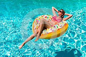 Woman takes a sunbath in a donut shaped pool float on a hot summer day