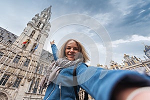 A woman takes a telephone picture on the background of the city hall in the main square Grand place in Brussels, Belgium
