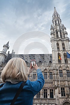 A woman takes a telephone picture of the city hall in the main square Grand place in Brussels, Belgium