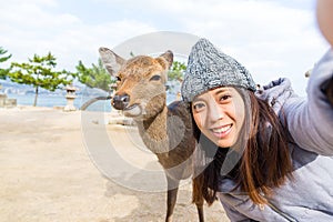 Woman takign selfie with deer in Itsukushima