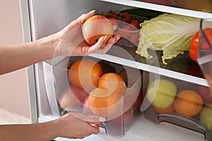 Woman taking apple from fridge