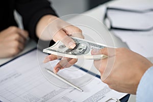 Woman taking batch of hundred dollar bills