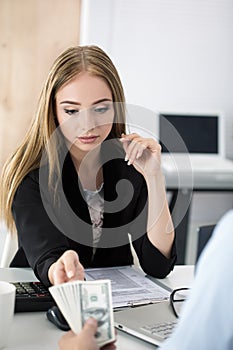 Woman taking batch of hundred dollar bills