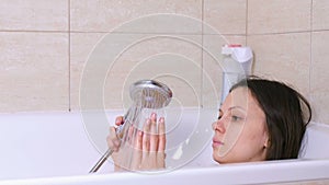 Woman is taking a bath. Relax after a bad day. Touch a water with hand.