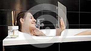 Woman taking a bath while staying connected with friends and family via a video call on her tablet computer. Authenticity and