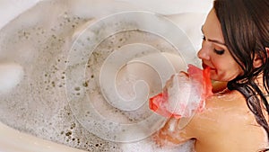Woman taking bath and wash sholder on foam in her bathroom.