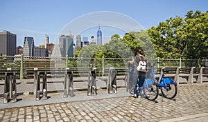 Woman taking a bike in front of Manhattan skyline in New York City
