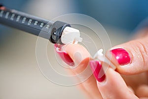 Woman taking blood sample with lancet pen. Diabetes.