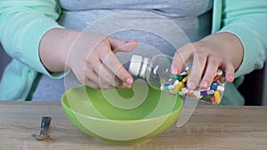 Woman taking bottle with pills and pouring them into bowl, medication overuse