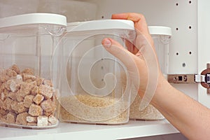 Woman taking brown rice from a kitchen cupboard