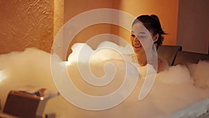 Woman taking a bubble bath in the bathtub at night