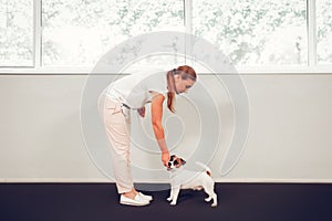 Woman taking care of cute dog standing near window