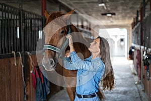Woman taking care of her horse in stable