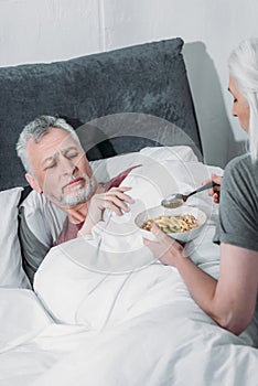 Woman taking care of sick husband in bed at home