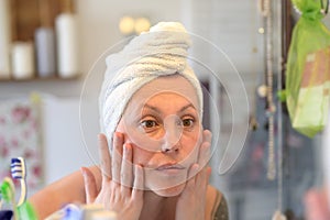 Woman taking a close look at her face in a mirror