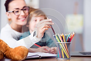 Woman taking a crayon from pencil cup