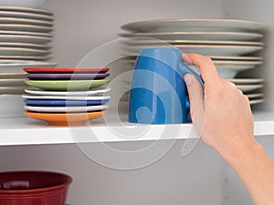 Woman taking a cup from a kitchen cabinet for breakfast