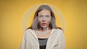 Woman taking a deep breath and exhale on a bright yellow background