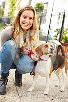 Woman Taking Dog For Walk On City Street