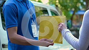 Woman taking envelope with documents from deliverer hands, door-to-door shipment photo