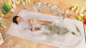 Woman taking foam bath and chiropody by wisp of bast in her bathroom.