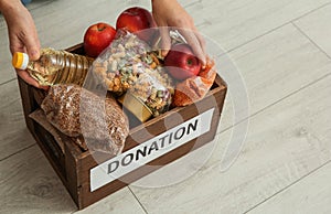 Woman taking food from donation box on wooden floor