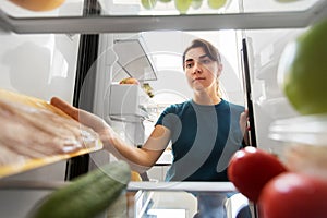 Woman taking food from fridge at home