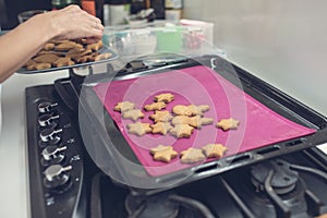 Woman taking freshly baked cookies off the hot tray