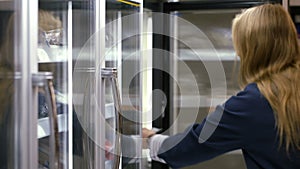 Woman taking frozen product from the fridge in the