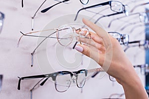 Woman taking glasses out of shelf in optician store