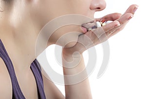 Woman taking handful pills over white background with copy space