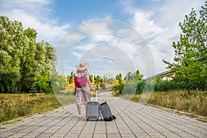 Woman is taking her luggage to the end of the road and looking forward.