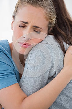 Woman taking her sad friend in her arms