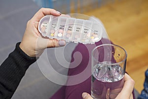 Woman taking medication. Woman holding a pills box and a glass of water. Healthcare concept with medicines