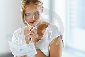 Woman Taking Medicine. Female With Pills Reading Instructions