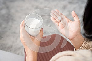 woman taking medicine hand holding a glass of milk