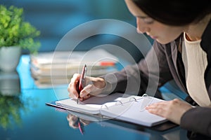 Woman taking notes on notebook in the night at home