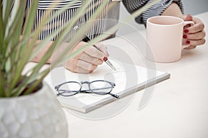 Woman taking notes whilst holding a cup of tea