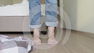 Woman taking off her clothe sin order to go to bed, bare feet close up, clothes falling down to the floor