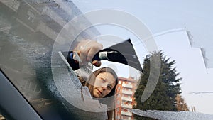 WoMan taking off ice from the windscreen