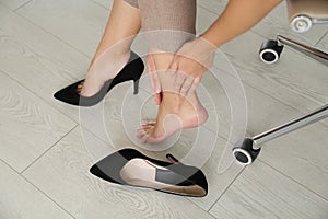 Woman taking off shoes in office, closeup. Tired feet after wearing high heels