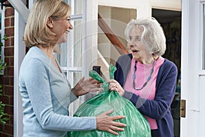 Woman Taking Out Trash For Elderly Neighbour