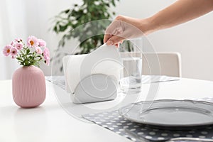 Woman taking paper tissue from ceramic napkin holder